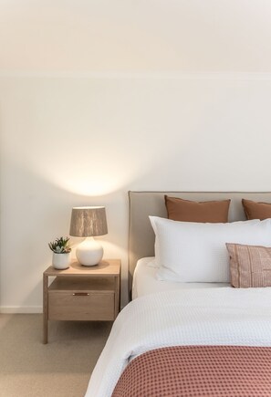 A bedroom with a bed, bedside table, lamp, and a small potted plant. - Heart of Sunshine Spacious Apt Pool and Garden (Noosa)