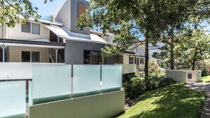 A modern residential building with a flat roof, large windows, and a well-maintained lawn. - Heart of Sunshine Spacious Apt Pool and Garden (Noosa)