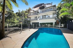 A multi-story residential building with a swimming pool, balconies, and surrounding palm trees. - Hamptons Style Beach Retreat in Noosa s Heart (Noosa)