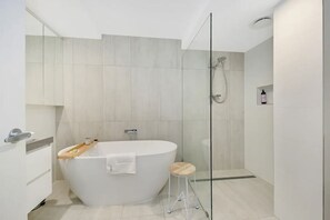 Ein modernes Badezimmer mit freistehender Badewanne, einer Duschkabine aus Glas und einem minimalistischen Design.