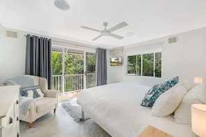 A bedroom with a bed, a chair, a ceiling fan, and large windows. - Hamptons Style Beach Retreat in Noosa s Heart (Noosa)