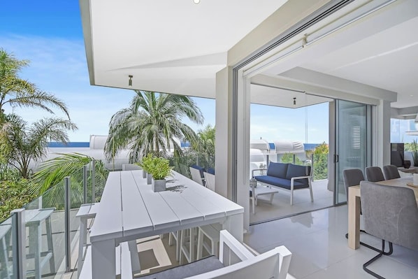 Relax in a spacious, open-plan room with a dining area and glass door leading to a serene outdoor space with a seating area.
