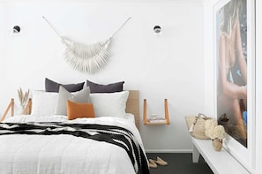 Cozy retreat with a neatly made bed, macrame wall decoration, and a shelf for your favorite reads.