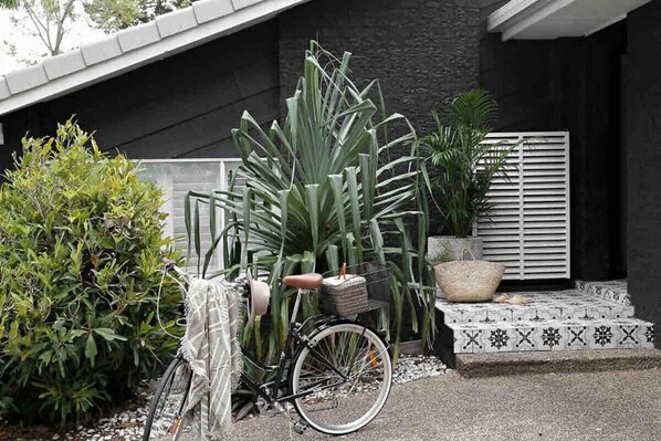 Bicycle parked in front of a building with a textured wall and patterned tile steps.