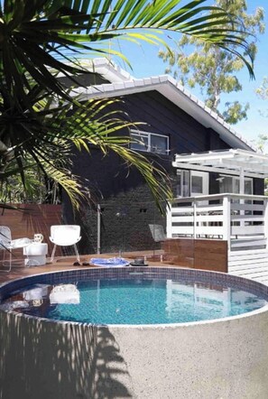 Relax by the pool surrounded by lush greenery and a shaded pergola.
