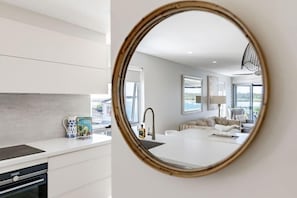 Eine moderne Küche mit weißen Schränken, einem integrierten Backofen und einer Arbeitsplatte mit Wasserkocher und Kaffeemaschine.