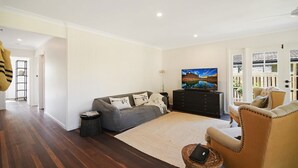 A living room with a sofa, armchair, TV, and a wooden coffee table.
