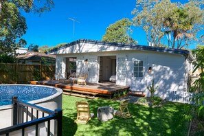 A single-story house with a covered patio, a swimming pool, and a small garden area.