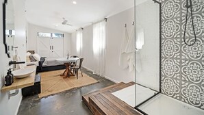 Et moderne badeværelse med en glasbrusekabine, en træbænk og et stort spejl.