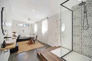 A modern bathroom with a glass shower enclosure, a wooden bench, and a large mirror. - The River Shack Vintage Luxe Right Beside River (Noosa)