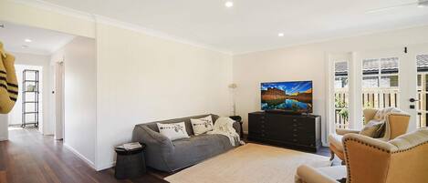 A modern living room with a grey sofa, a black entertainment unit, and a large flat-screen TV.