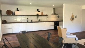 A modern kitchen with white subway tiles, a wooden dining table, and a seating area with a cushioned chair.