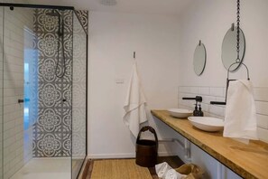 A bathroom with a glass shower enclosure, a wooden vanity with two sinks, a mirror, and a towel rack. - The River Shack Vintage Luxe Right Beside River (Noosa)