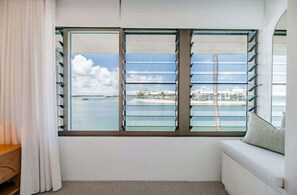A room with a large window, a white sofa, and a wooden bench. - Bella Vista Noosa Luxury on White Sands (Noosa)