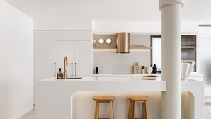 Een moderne keuken met witte kasten, een centraal eiland met krukken en een grote kolom.
