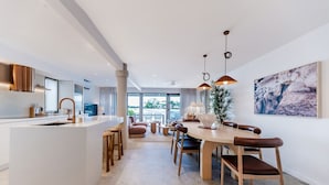 Een moderne keuken met een centraal eiland, een eethoek met houten stoelen en een groot raam met uitzicht.