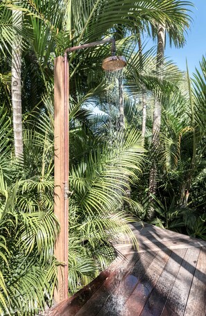 A wooden pergola with a water feature, surrounded by lush green foliage.