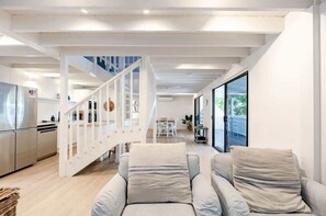 A modern interior with a staircase, a kitchen, and a seating area with a view.