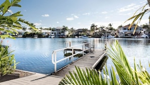 A marina with docked boats, a wooden pier, and houses in the background. - Seahorse Family & Pooch Friendly Waterfront Home (Noosa)