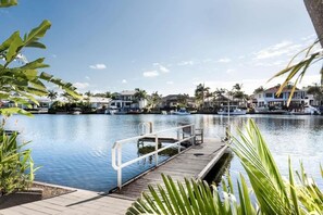 A marina with boats docked, a wooden dock, and residential buildings in the background. - Seahorse Family & Pooch Friendly Waterfront Home (Noosa)