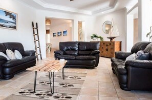 A living room with leather sofas, a wooden coffee table, and a decorative sailboat. - Seahorse Family & Pooch Friendly Waterfront Home (Noosa)