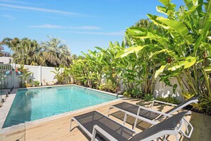 A rectangular pool with clear blue water, surrounded by lush green foliage and palm trees. - Seahorse Family & Pooch Friendly Waterfront Home (Noosa)