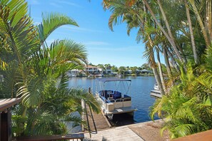 A marina with boats docked, surrounded by palm trees and houses in the background. - Seahorse Family & Pooch Friendly Waterfront Home (Noosa)