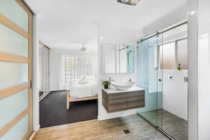 Une salle de bain moderne avec une douche à parois de verre, un lavabo blanc et un grand miroir.