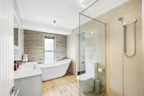 Un baño moderno con una bañera independiente, ducha con mampara de vidrio y un inodoro.
