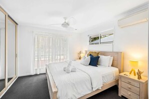 Ein Hotelzimmer mit Bett, Nachttisch, Schreibtisch und Deckenventilator.