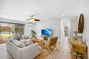 Ein stilvolles Wohnzimmer mit grauem Sofa, Couchtisch aus Holz und Fernseher, der eine Welle zeigt.