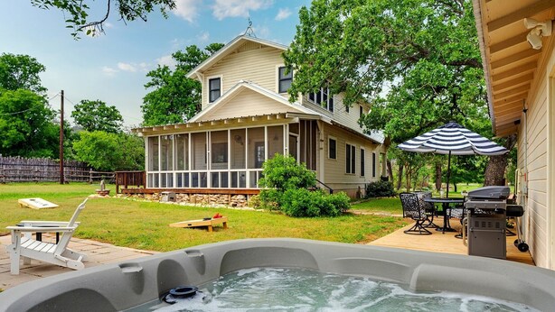 Una casa con un porche mosquitero, un jacuzzi y muebles de exterior.