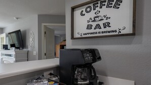 Segno di un bar con una macchina da caffè e cialde per caffè sul bancone.