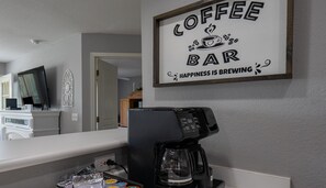 A coffee bar sign with a coffee machine and coffee pods on the counter.