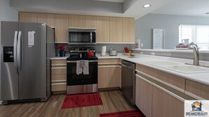 Una cucina moderna con elettrodomestici in acciaio inossidabile, mobili in legno e un tappeto rosso.