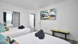 Habitació d'hotel amb dos llits, una banca, una televisió i una porta que dóna a un armari.