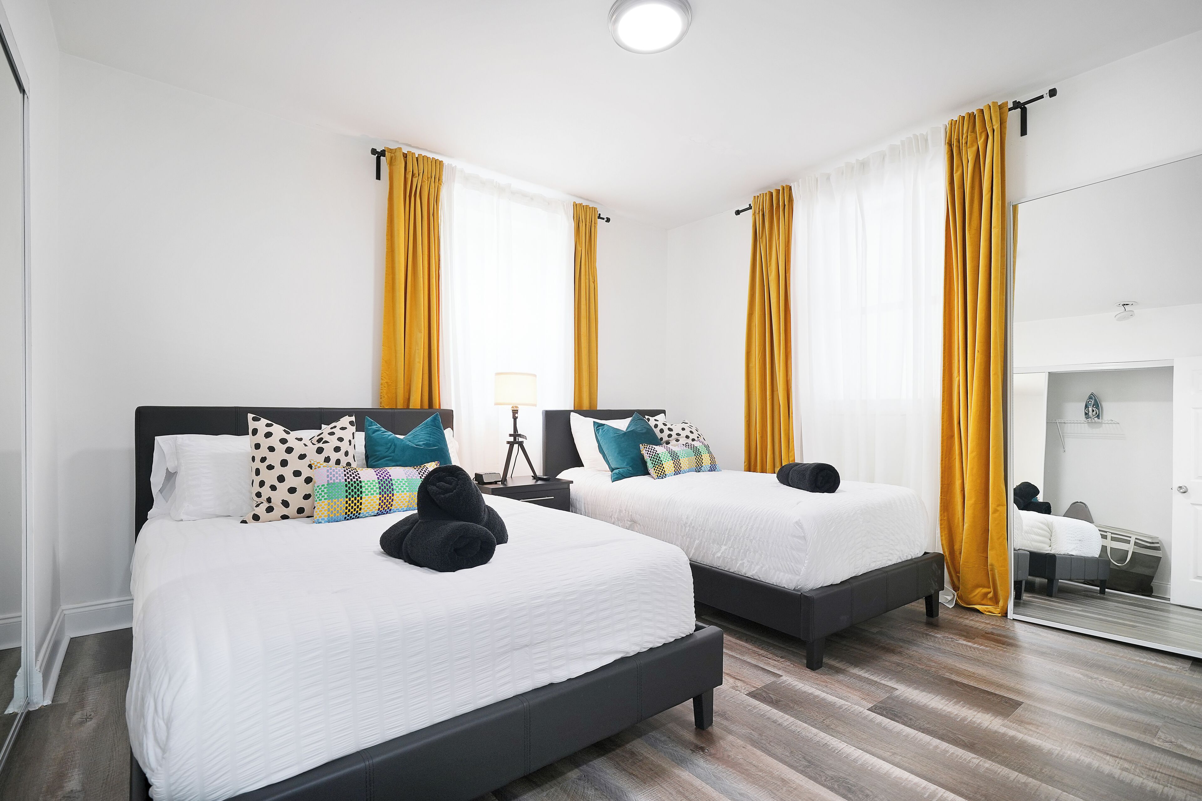 Een hotelkamer met twee bedden, een spiegel en een houten vloer.