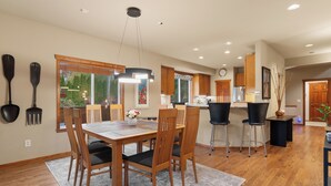A modern kitchen with wooden cabinets, a dining area with a wooden table and chairs, and a bar area with stools. - Poppyrosa Estate with mountain views minutes from Seattle, Bellevue, Sea-Tac (Issaquah)