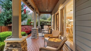 A covered patio with wicker furniture, stone pillars, and a view of the backyard. - Poppyrosa Estate with mountain views minutes from Seattle, Bellevue, Sea-Tac (Issaquah)
