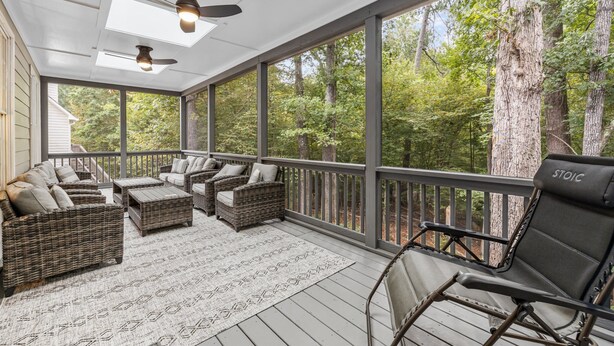 A covered porch with wicker furniture, a ceiling fan, and a view of the forest. - Stunning 5 bedroom/3 bath home in Hope Valley Farm (Durham)