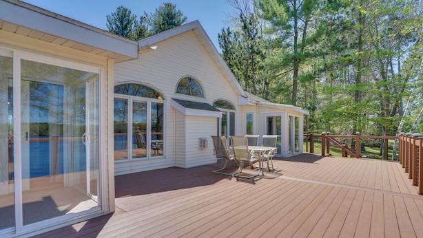A wooden deck with a glass door leading to a covered patio area. - Spacious Lakefront New Auburn Home w/ Sunroom (New Auburn)