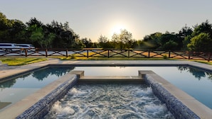 A swimming pool with a waterfall feature, surrounded by a wooden fence and trees. - Outdoor Pool & Patio: Quiet Whitney Retreat! (Whitney)