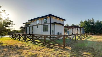 Situated in a serene grassy area, this house features a two-story design with a flat roof and a balcony on the upper floor.