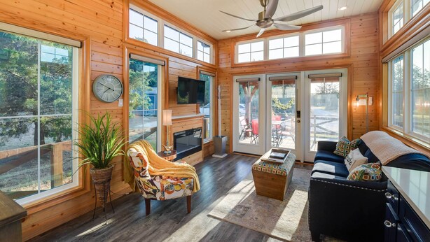 A spacious living area with a fireplace, large windows, and a ceiling fan. - Outdoor Pool & Patio: Quiet Whitney Retreat! (Whitney)