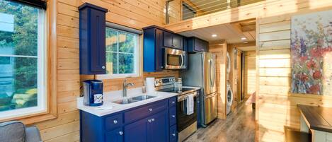 Una cocina moderna con paredes de madera, un refrigerador de acero inoxidable y un microondas.