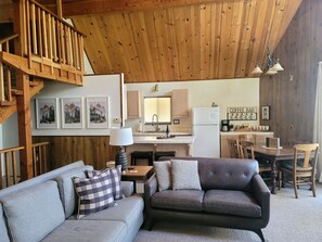 Una sala de estar acogedora con sofá, barra de café y zona de cocina.