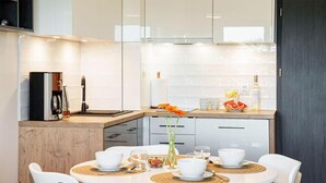 Una cucina moderna con mobili bianchi, una macchina da caffè e un'area pranzo con sedie bianche e un tavolo rotondo.