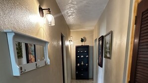 A hallway with a marble floor, wall-mounted light fixtures, and a door at the end. - Scott Beach Villa #3 (St Thomas)