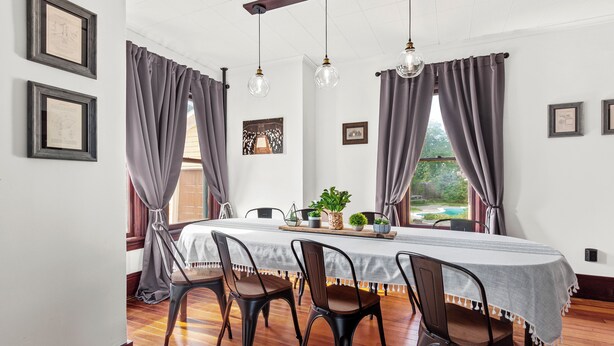 Un espace repas comprenant une longue table, quatre chaises et un lustre.