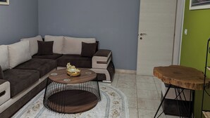Una sala de estar con un sofá modular, una mesa de centro redonda, una alfombra y una mesita de madera.